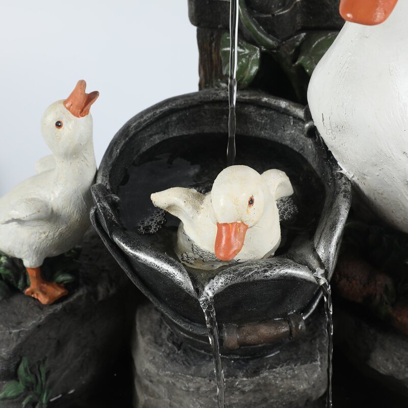Decorative fountain with goose figures and a running faucet.