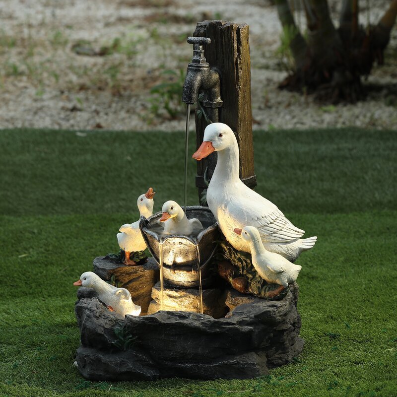 Garden fountain with ducks on a grassy background