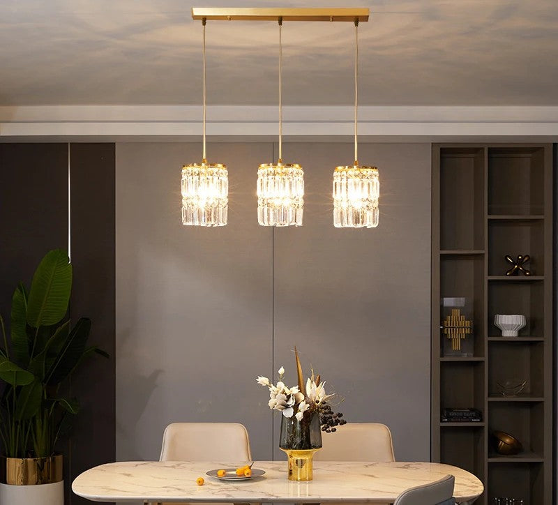 Modern dining room with three hanging crystal lights, a table, and decor.
