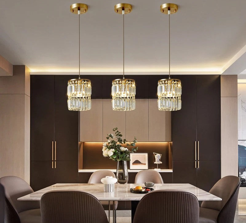 Modern dining room with crystal pendant lights, marble table, and chairs.