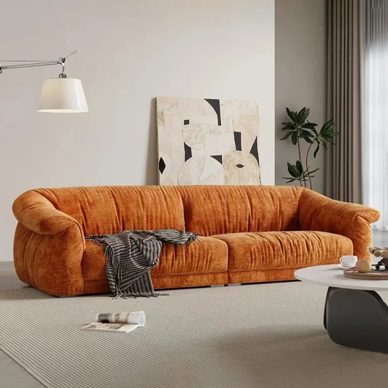 Orange sofa in a living room with abstract art and a coffee table.