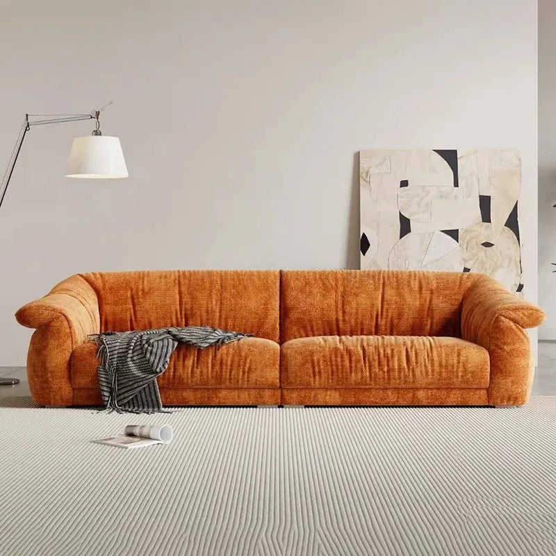 Orange sofa in a living room with a lamp and abstract painting on the wall.