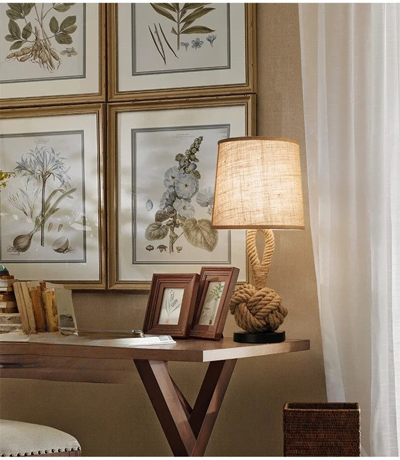 Decorative lamp on a table with framed botanical prints on the wall.