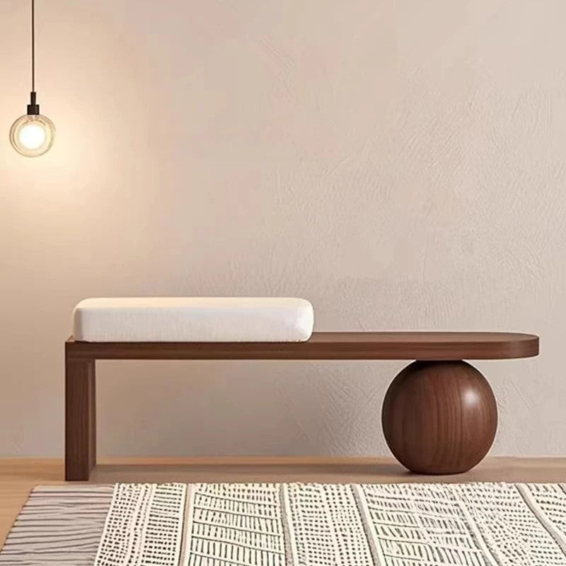 Wooden bench with spherical end piece in a minimalistic room.
