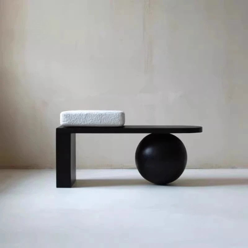 Minimalist black table with a sphere and cushion on a plain background