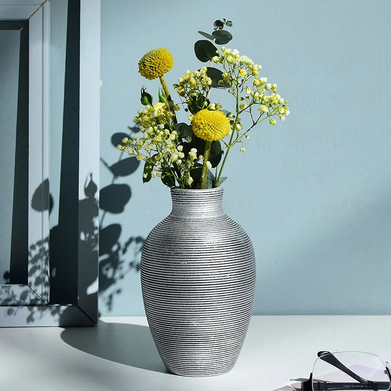 Gray textured vase with yellow flowers on a light blue wall background