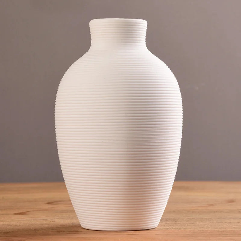 White ribbed vase on a wooden surface with a gray background