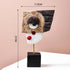 A modern and abstract resin figurine featuring geometric patterns in black, brown, and white, with a gold base.