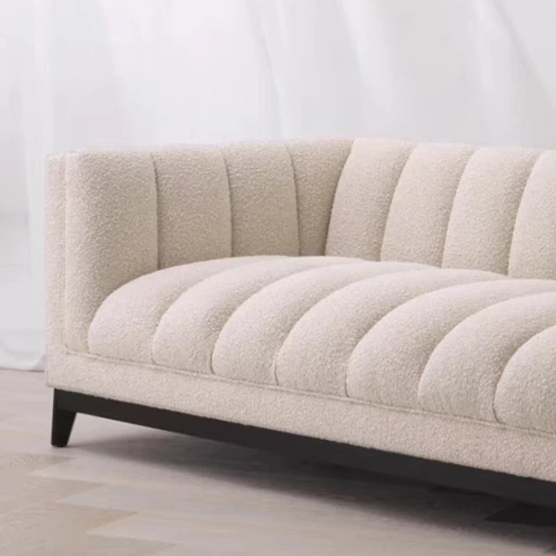Beige sofa with a quilted design on a light wooden floor and white wall background