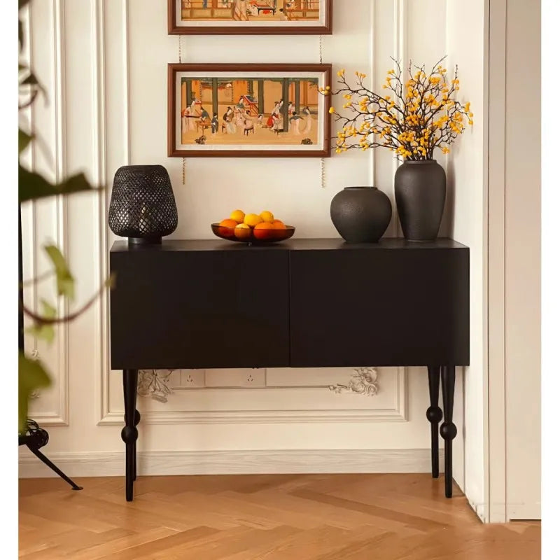 Black sideboard with decorative items in a room with framed art on the wall.