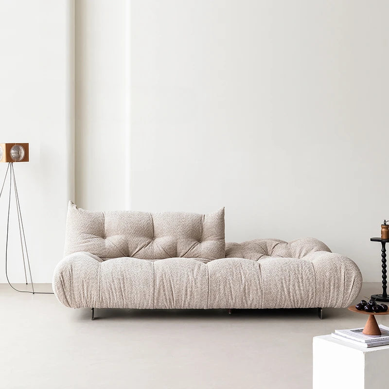 Beige sofa in a minimalistic room with white walls and a small table.