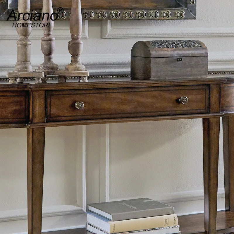 Wooden console table with decorative items against a neutral wall, featuring the Arcadian HomeStore brand.