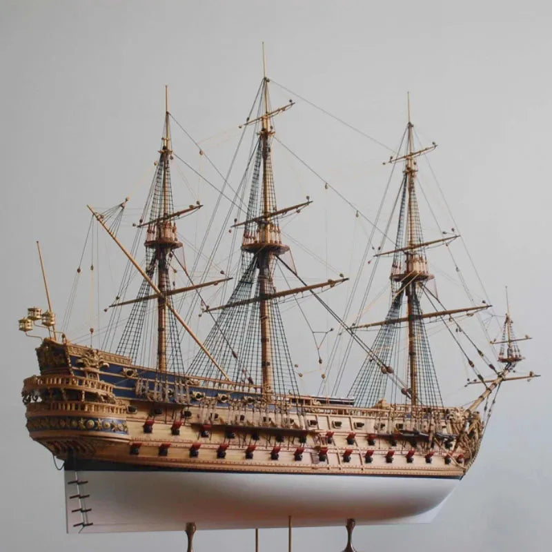 Model of a three-masted sailing ship on a gray background