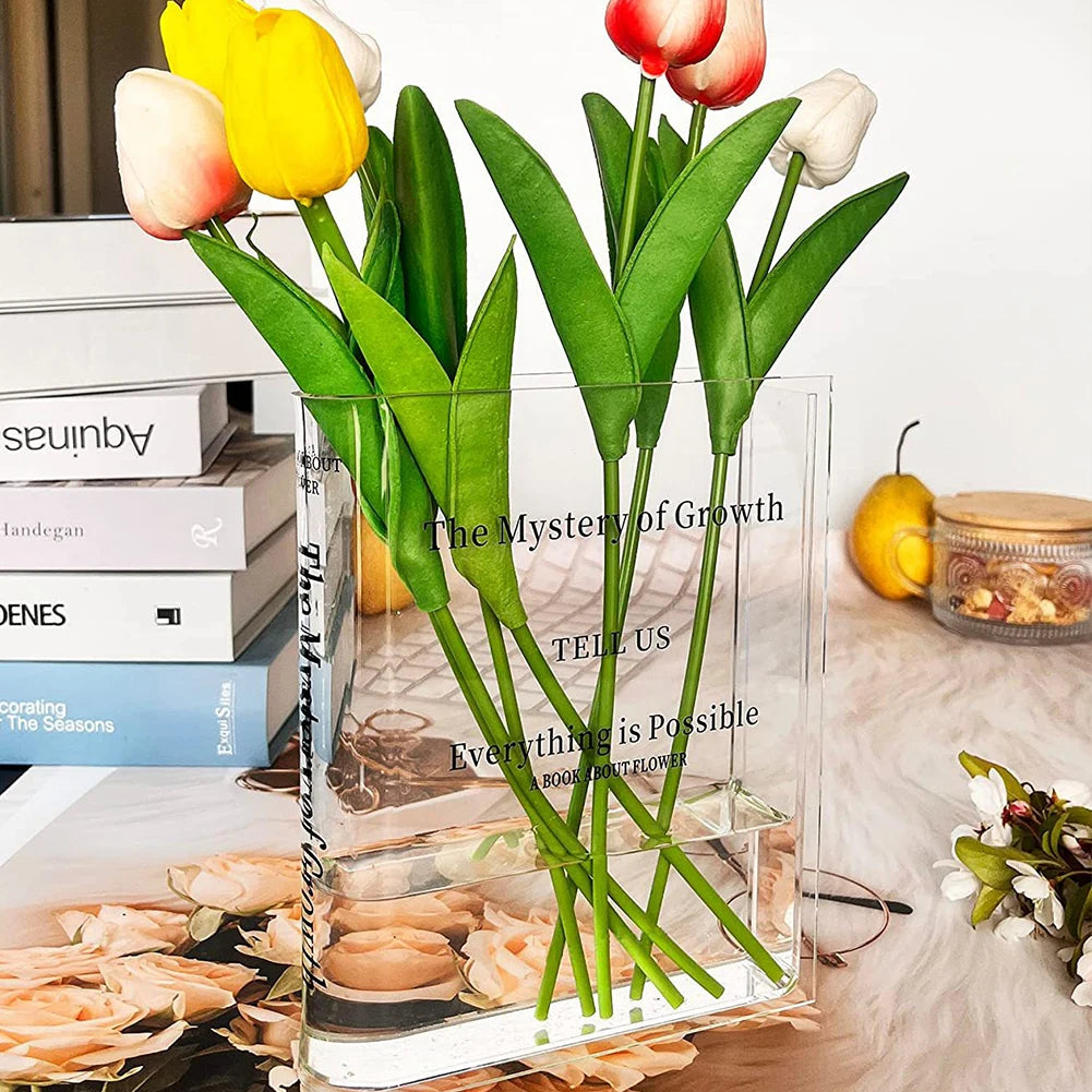 Clear vase with artificial tulips on a surface with books and decorative items.