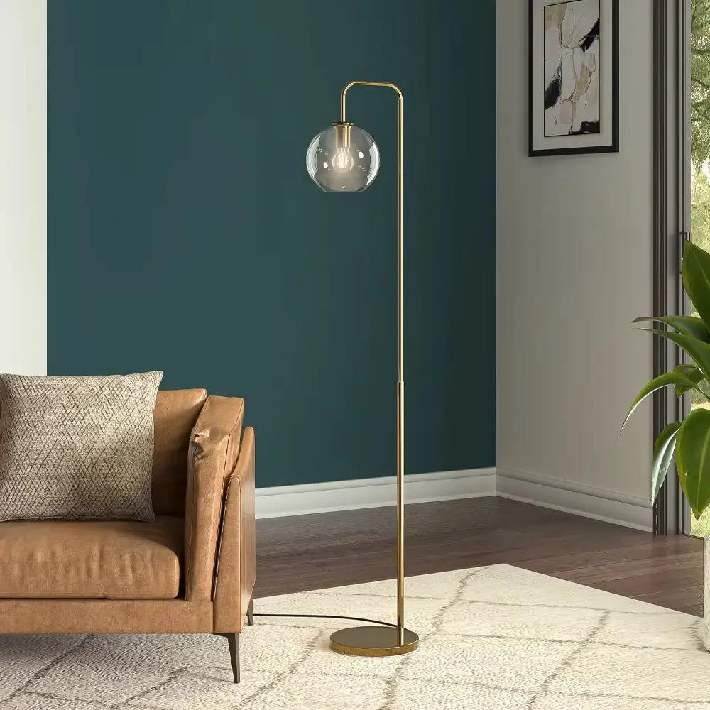 Gold floor lamp with a glass shade in a living room setting.