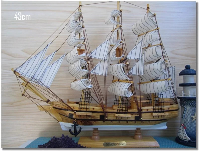 Model ship with multiple sails on a wooden base against a light background