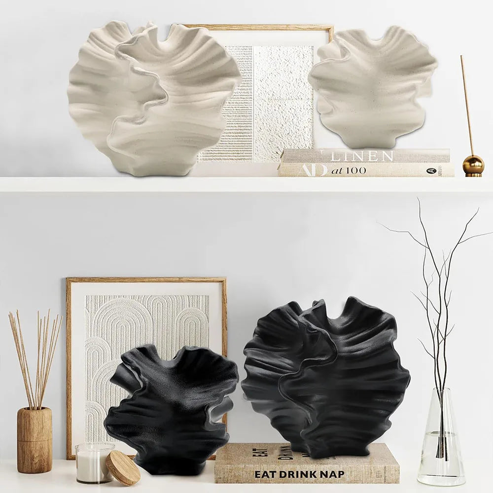 Decorative black and white vases on a shelf with books and a plant.