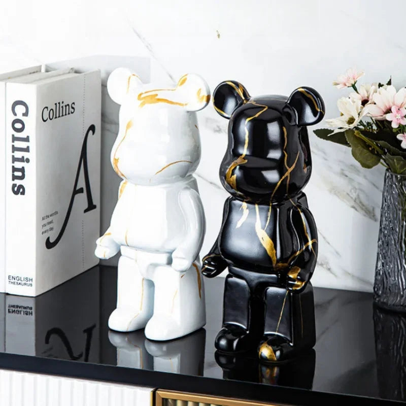 Two decorative bear statues, one white and one black with gold accents, on a reflective surface.