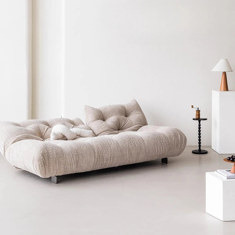 Beige sofa in a minimalistic room with a white wall and light-colored floor.