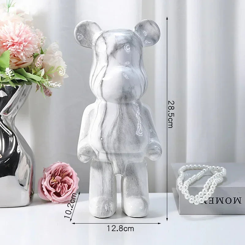 Silver marble bear figurine with measurements on a white surface with decorative items.