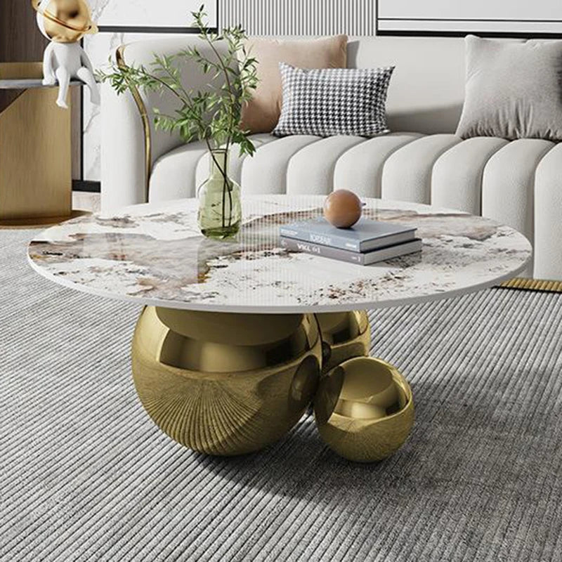 A modern round coffee table with a minimalist metal design featuring a Moroccan-inspired pattern, placed on a striped rug in a contemporary living room setting.