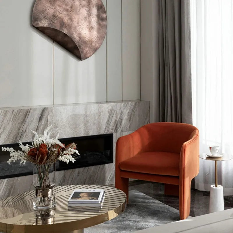 Modern living room with an orange armchair, round coffee table, and decorative elements.