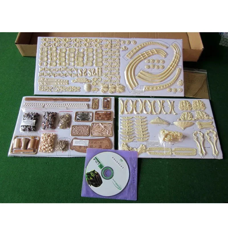 Decorative modeling kit with various pieces and a CD on a green surface