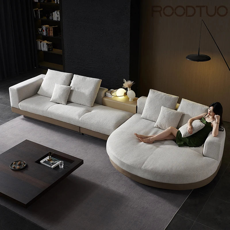 Modern living room with a white sectional sofa and a woman sitting on it.