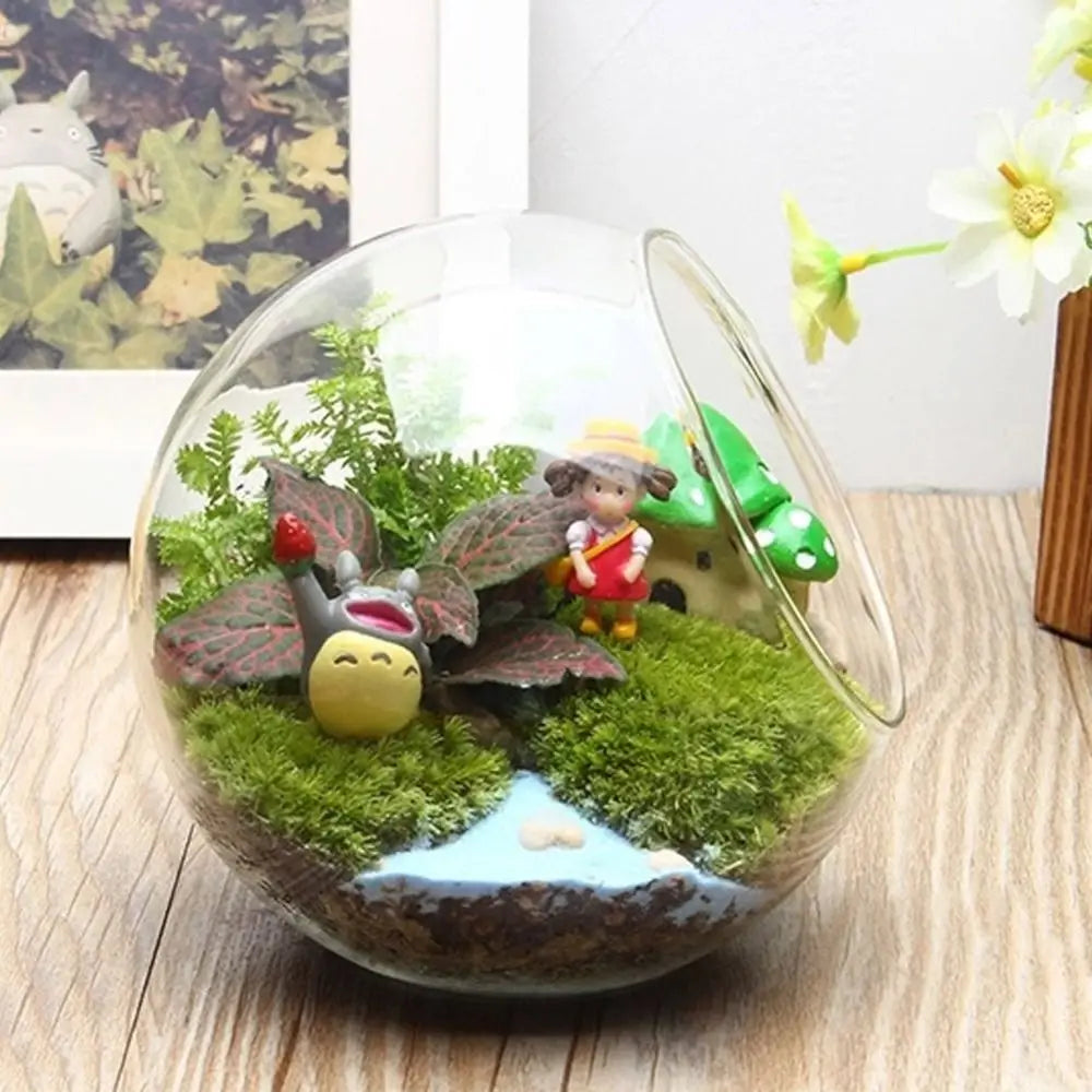 Terrarium with miniature figures and plants on a wooden surface