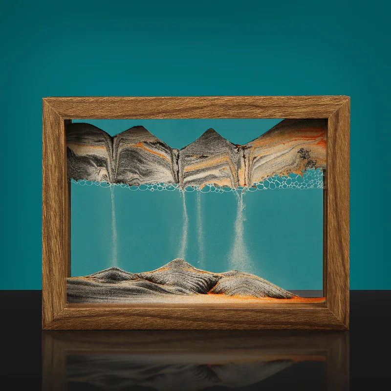 Wooden frame with a sand sculpture of mountains on a teal background