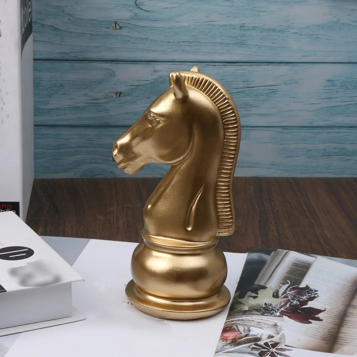 Gold chess piece resembling a horse on a wooden surface with a blue wooden panel background