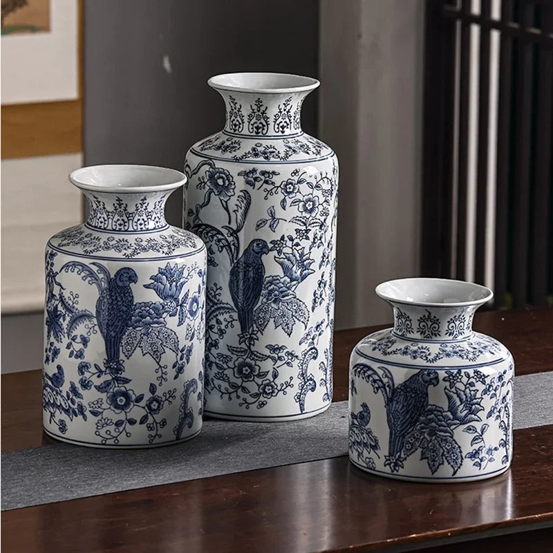 Three blue and white ceramic vases with floral and bird patterns on a wooden surface.