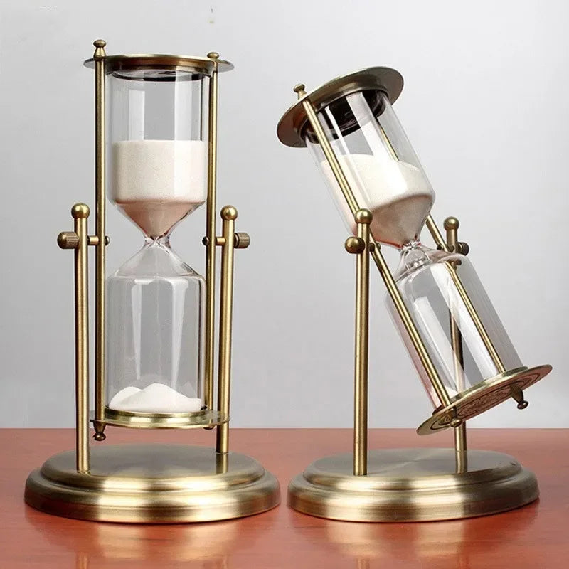 Two vintage-style hourglasses with brass frames on a wooden surface.
