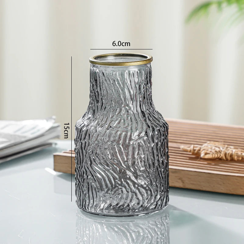 Glass vase with textured design and gold rim on a reflective surface, with measurements indicated.