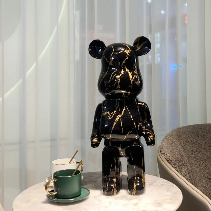 Black and gold marble-patterned bear statue on a table with a cup and saucer in the background.