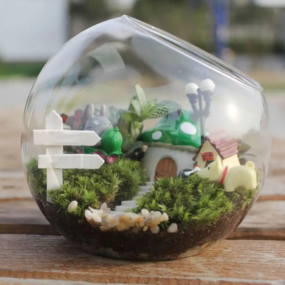 Miniature garden scene in a transparent dome on a wooden surface
