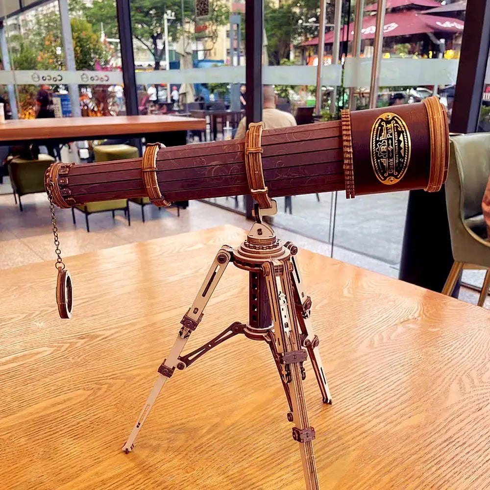 Steampunk-style telescope model on a wooden table with a blurred cafe background