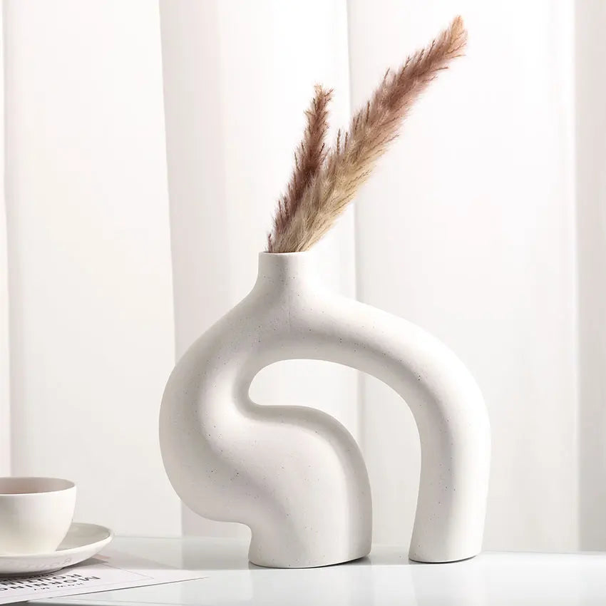 White abstract vase with dried pampas grass on a white surface