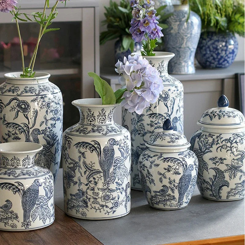 Set of decorative blue and white ceramic vases on a surface with flowers.