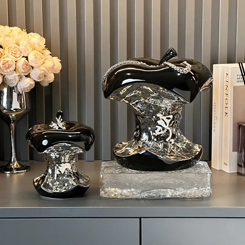 Decorative black and silver mushroom sculptures on a shelf with books and flowers in the background.