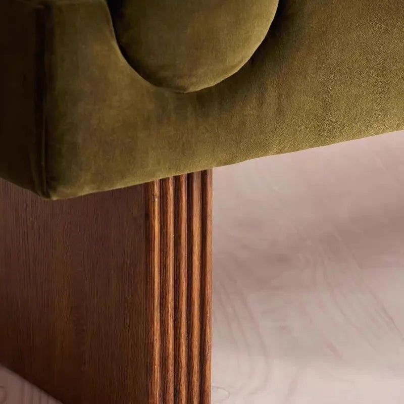 Close-up of a green upholstered headboard with wooden legs on a bed.