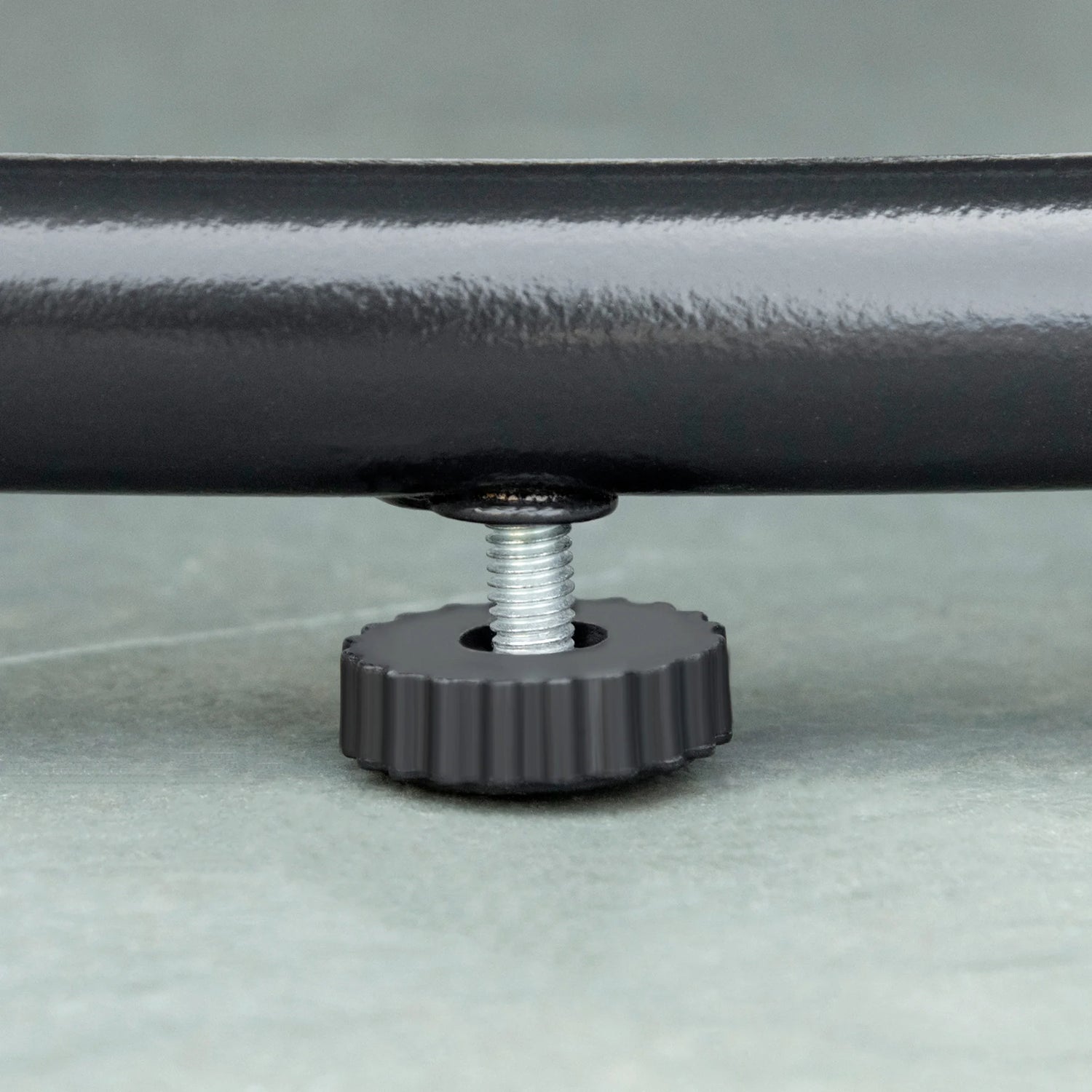 Close-up of a metal bracket with a wheel on a gray background
