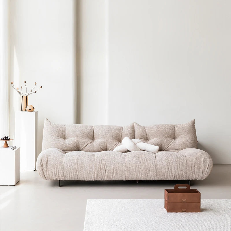 Beige sofa in a minimalistic living room with a white wall and light-colored floor.
