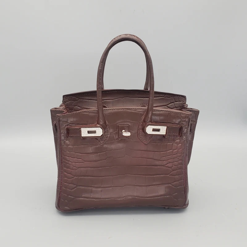 Brown crocodile skin handbag with silver hardware on a light grey background  Handbag design flower holder