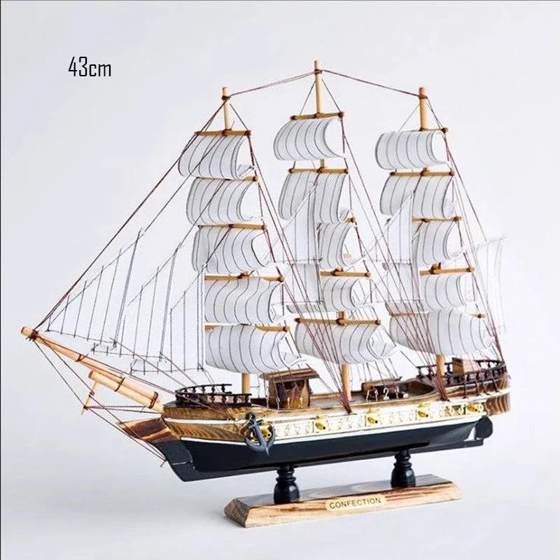 Model sailboat with multiple sails on a light gray background