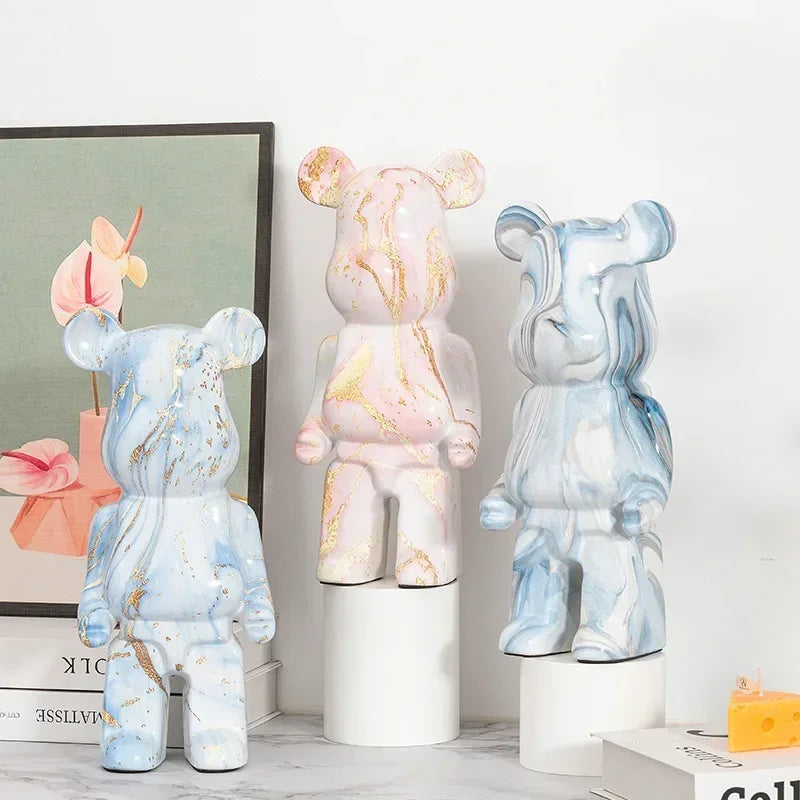 Three marble-patterned bear figurines on a white surface with a light gray wall in the background.