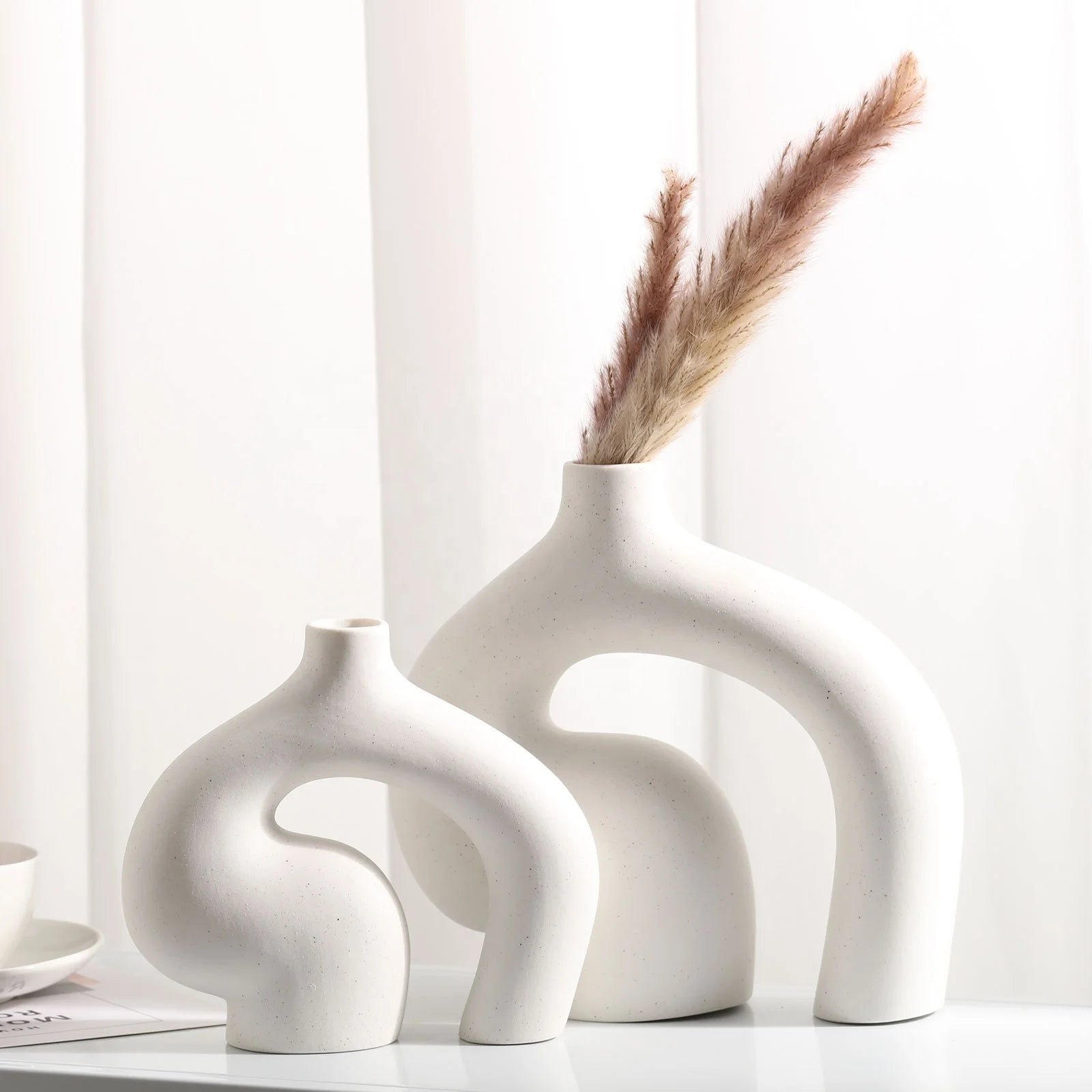 Set of three white ceramic vases on a light surface with a neutral background