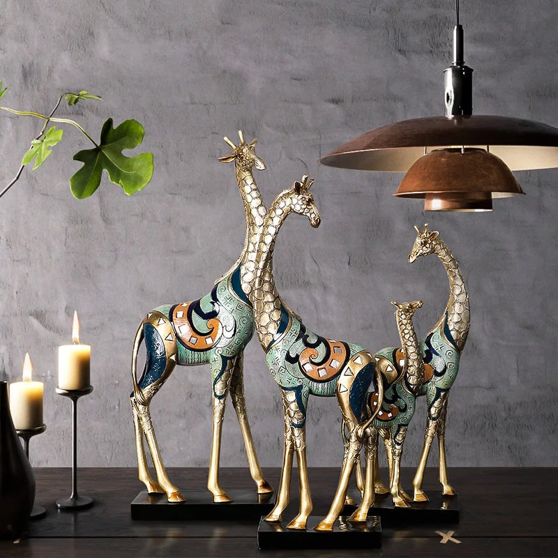 Decorative giraffe statues on a dark surface with a gray wall and lamp in the background.