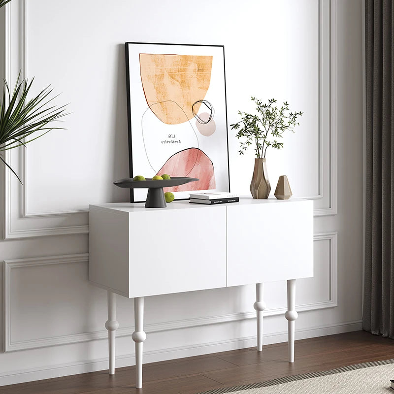 White console table with decorative items against a wall with framed artwork.