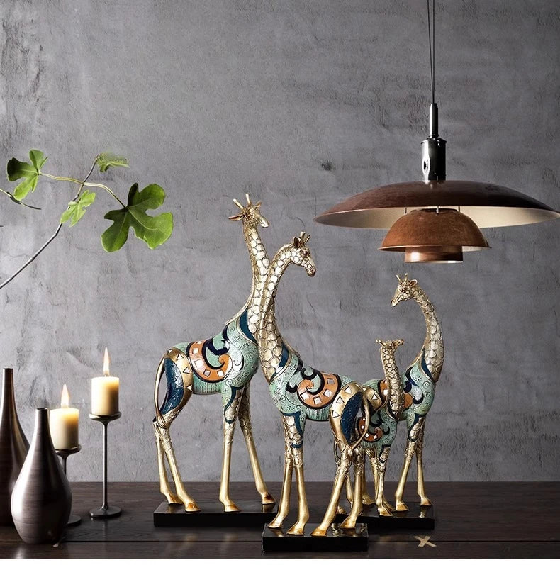 Decorative giraffe statues on a wooden surface with a gray wall and pendant light in the background.